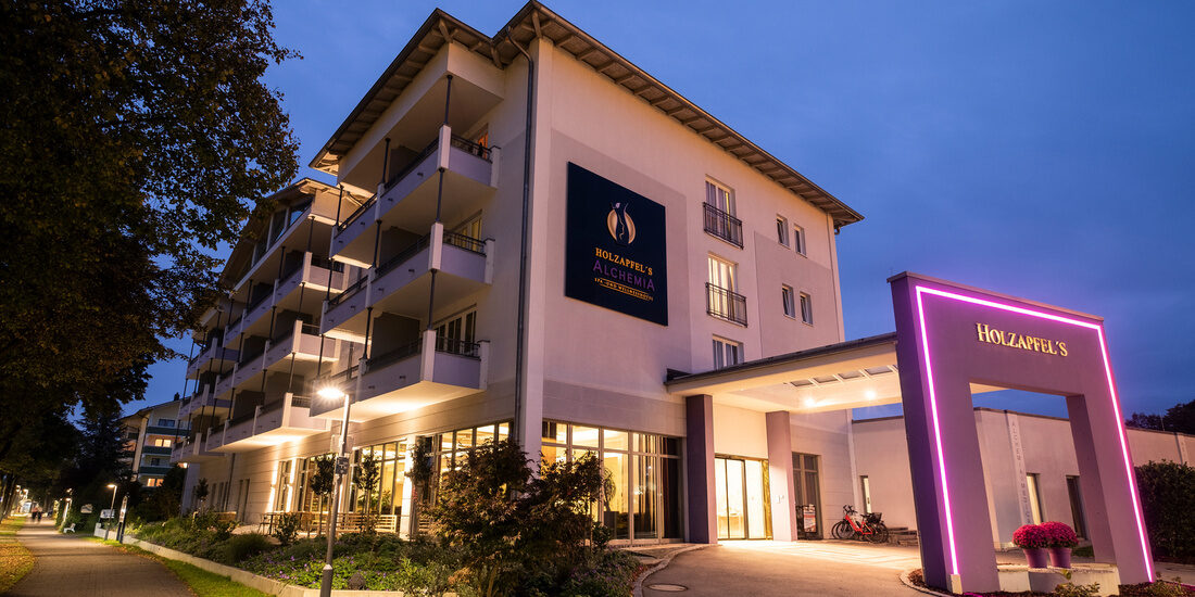 Das Hauptgebäude des Thermenhotels Holzapfel in Bad Füssing leuchtet nachts und bietet eine stimmungsvolle Atmosphäre.