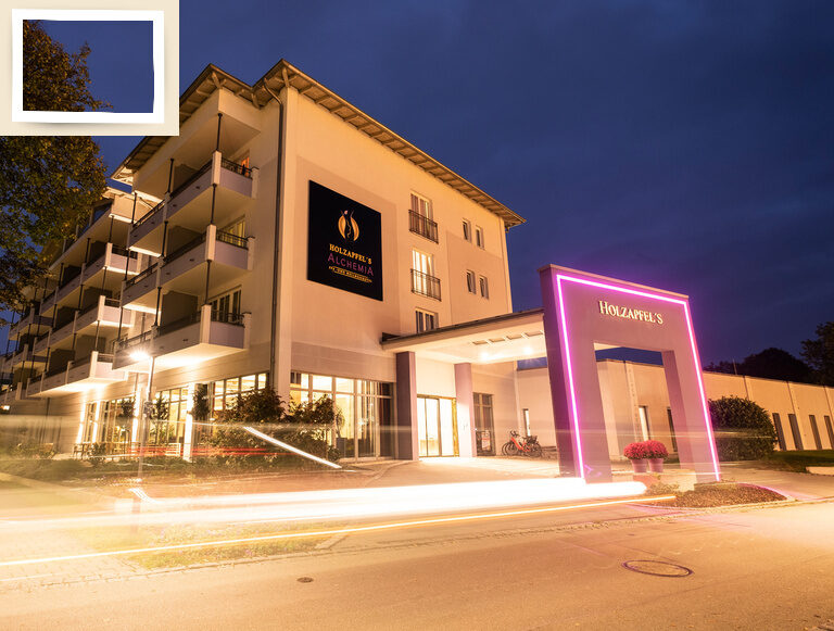 Der beleuchtete Eingangsbereich des Seminarhotel Holzapfel am Abend.
