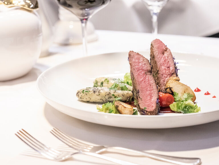 Ein kunstvoll angerichtetes Fleisch- und Gemüsegericht im Holzapfel's Restaurant im Glockenturm in Bad Füssing.
