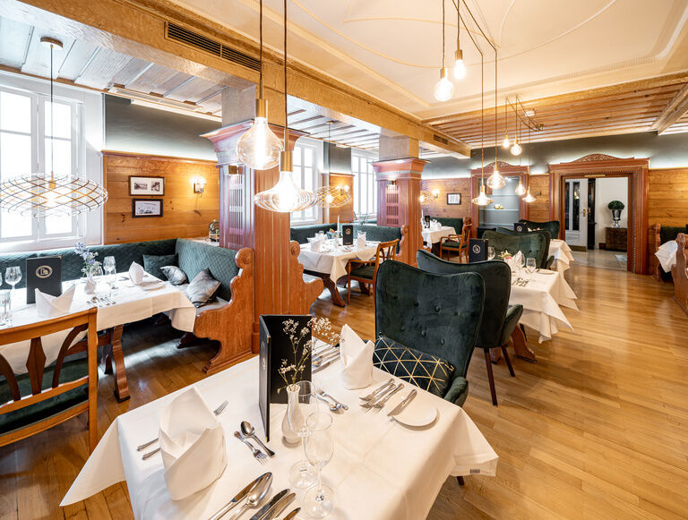 Ein gemütlicher Essbereich mit edlen gedeckten Tischen in der Schwarzwaldstube des Hotelrestaurants Holzapfel in Bad Füssing.
