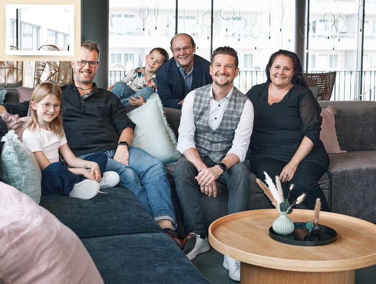 Die Gastgeberfamilie des Wellnesshotels Holzapfel sitzt zusammen lächelnd auf einer Couch