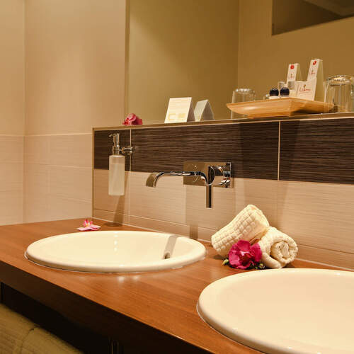 Luxuriös ausgestattetes Badezimmer im Wellnesshotel Holzapfel mit doppelten Waschbecken und einem großen Spiegel.
