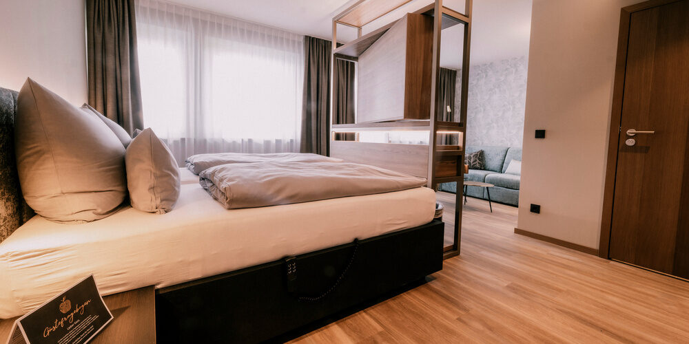 Stilvolle Doppelzimmer Comfort Raumansicht mit gemütlichem Doppelbett und Sitzmöglichkeiten im Wellnesshotel Holzapfel in Bayern.