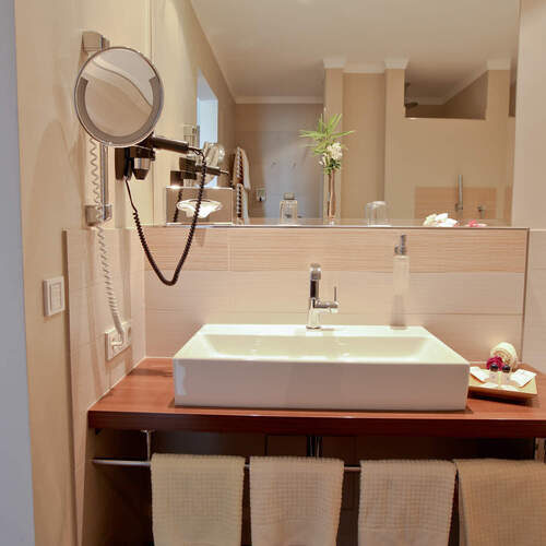 Der Waschbeckenbereich im Doppelzimmer Deluxe Ost des Wellnesshotels Holzapfel mit natürlichem Licht und gepflegtem Design.