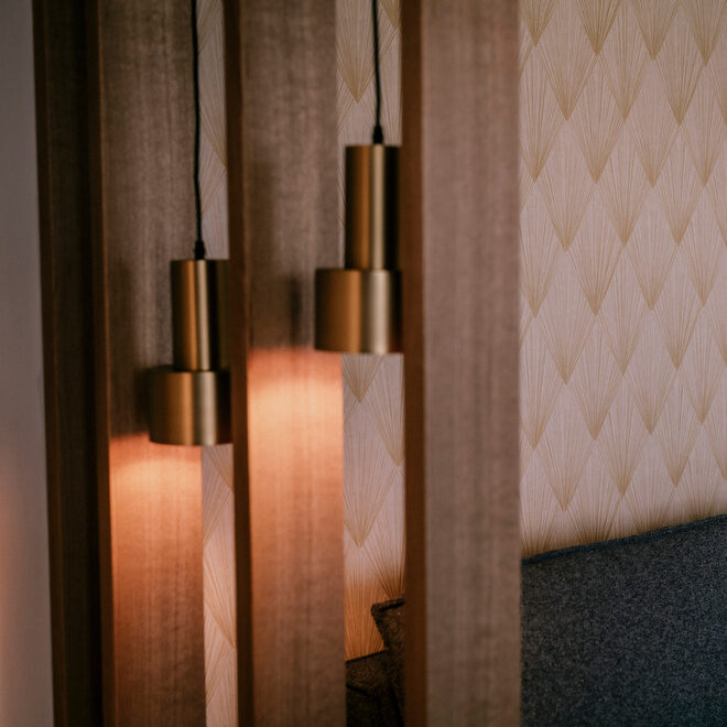 stilvoller Wohnraum mit einem gemütlichen Sofa und zwei designorientierten Lampen im luxuriösen Hotel Holzapfel im Rottal.