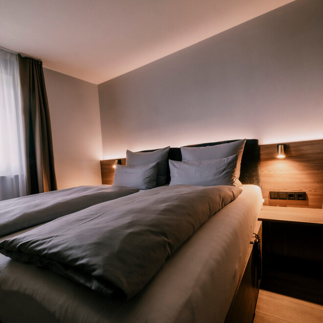 Gemütliches Doppelbett im stilvoll gestalteten Doppelzimmer Standart des Wellnesshotel Holzapfel in Bad Füssing.