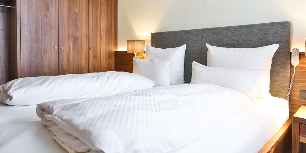 Einladendes Bett mit weißen Kissen und Decke im Doppelzimmer Standart des Thermenhotels Holzapfel in Bayern.