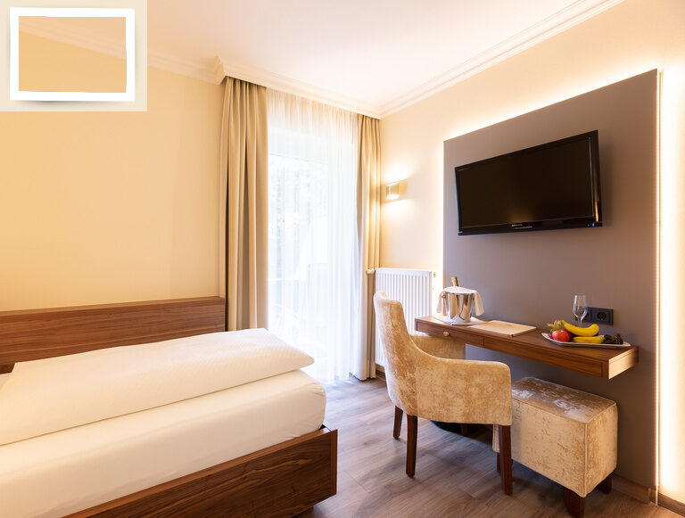 Schlafzimmer im Einzelzimmer Standard des Wellnesshotels Holzapfel mit einem komfortablen Bett, Schreibtisch und Fernseher.