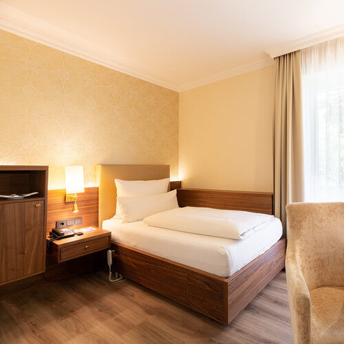 Modernes Einzelzimmer Standard im Wellnesshotel Holzapfel mit einem Bett, Schreibtisch und Fernseher.