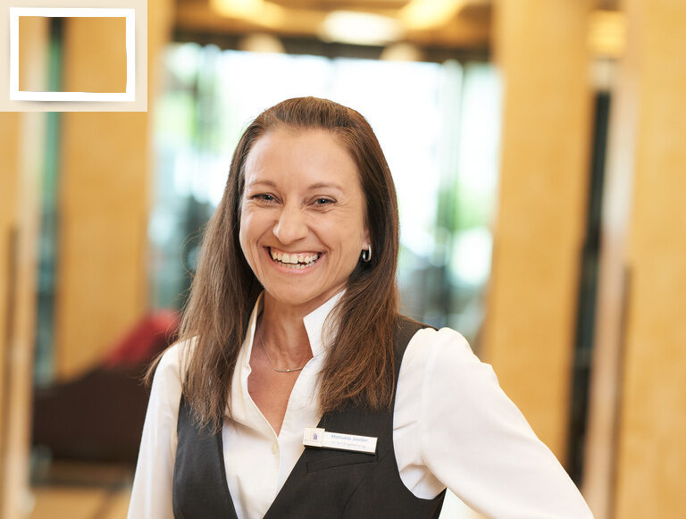 Teammitglied Empfangsleitung Manuela Jordan zeigt einen fröhlichen Gesichtsausdruck im Hotel Holzapfel in Bad Füssing.