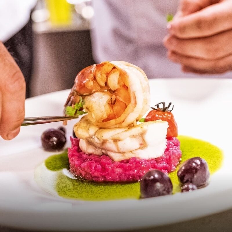Ein raffiniert angerichtetes Fischgericht auf einem weißen Teller im Restaurant Glockenturm des Wellnesshhotels Holzapfel in Niederbayern..