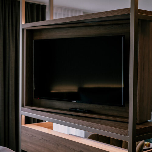 Ein Flachbildfernseher zur Unterhaltung auf einem hölzernen Schrank im Doppelzimmer Comfort - Wellnesshotel Holzapfel in Niederbayern.