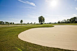 Ein weitläufiger grasgrüner Golfplatz unter strahlend blauem Himmel in der Nähe von Bad Füssing.