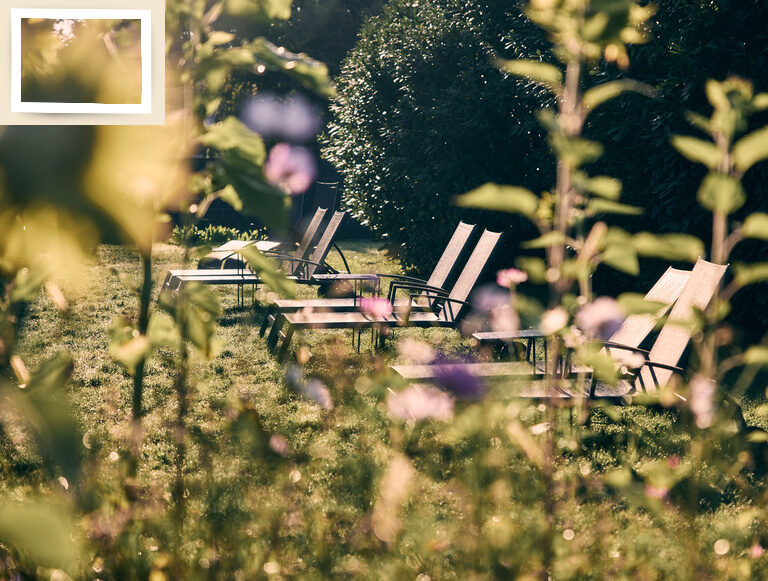 Gartenliegen inmitten von farbenfrohen Blumen im Aussenbereich des Thermenhotels Holzapfel im Kurort Bad Füssing.