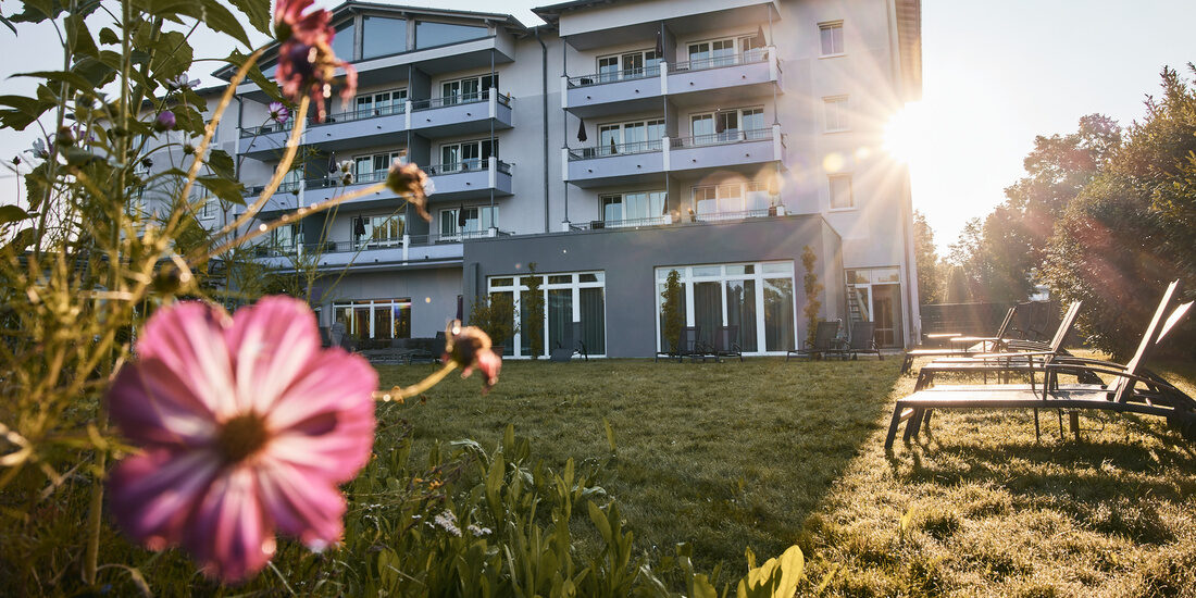 Das einladende Hotel Holzapfel umrahmt von lebendigen Blumen und Wiesen.