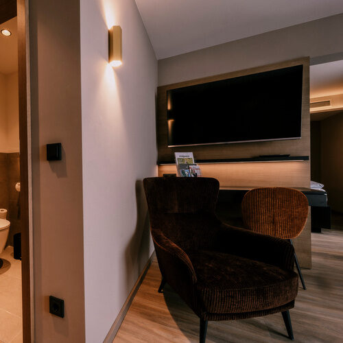 modern eingerichtetes Zimmer im Thermenhotel Holzapfel bei Passau mit Bett, Stuhl und Flachbildfernseher.