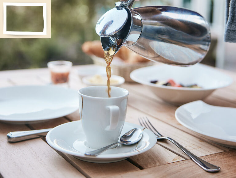Eine Person schenkt frisch gebrühten Kaffee in eine Tasse auf der Terrasse des Wellnesshotels Holzapfels in Niederbayern ein.
