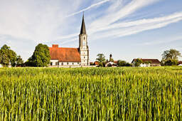 Eine Kirche ist umgeben von landwirtschaftlichen Feldern in der Region Bad Füssing.