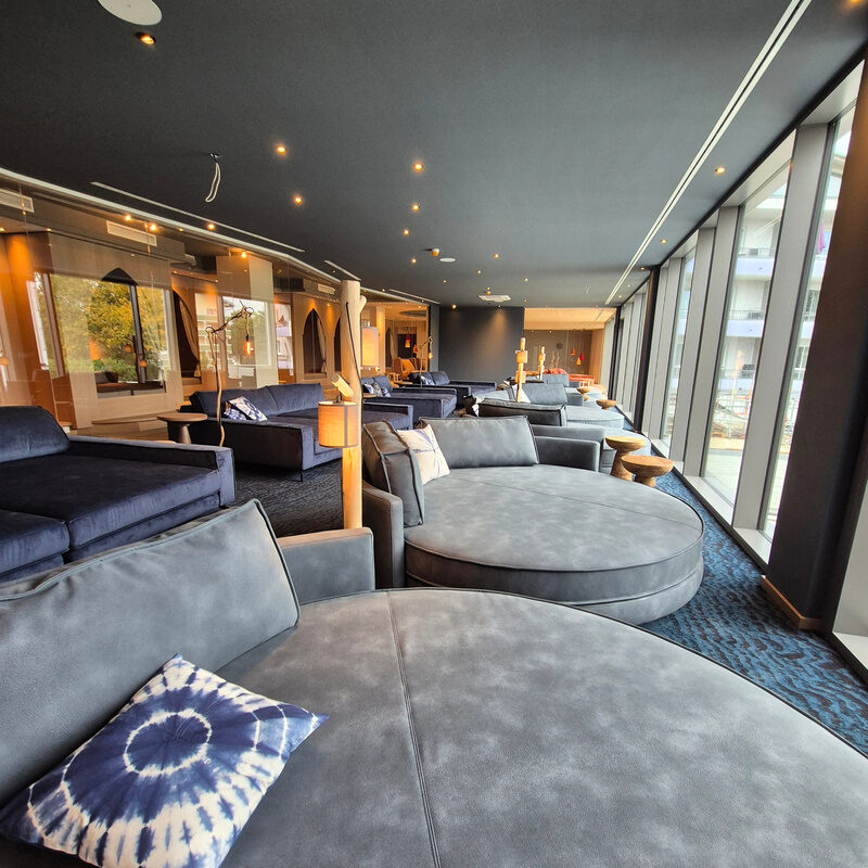 Geschmackvoll gestalteter Ruheraum des Wellnesshotel Holzapfel Bad Füssing mit runden Liegecouchen und großen Fenstern mit Panoramaausblick.