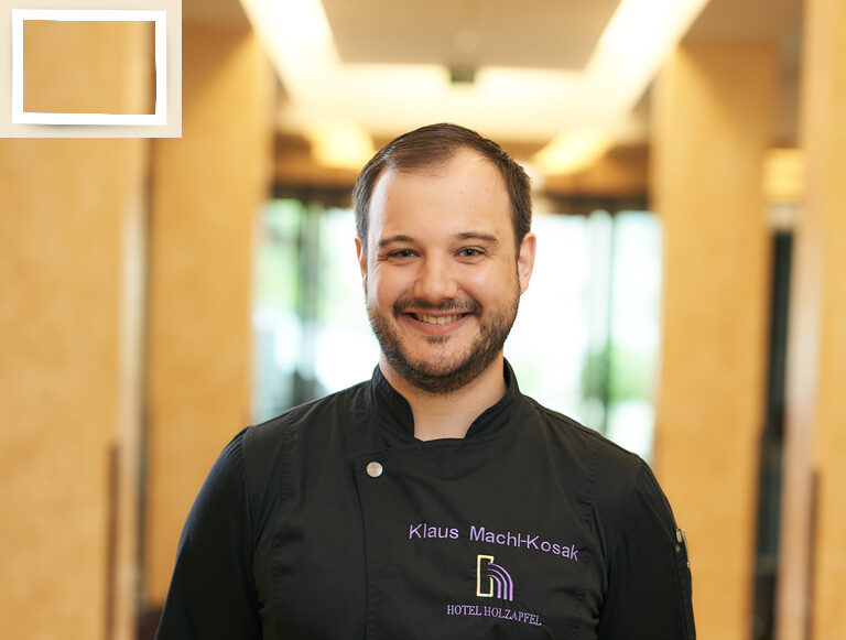 Der Küchenchef Klaus Machl Kosak mit freundlicher Gesichtsausdruck, gekleidet in Arbeitskleidung im Hotel Holzapfel in Bayern..