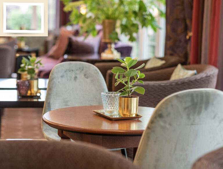 Ein stilvoller Tisch mit Stühlen und einem Blumenstrauß im Lounge-Bereich des Fitnesshotel Holzapfel.