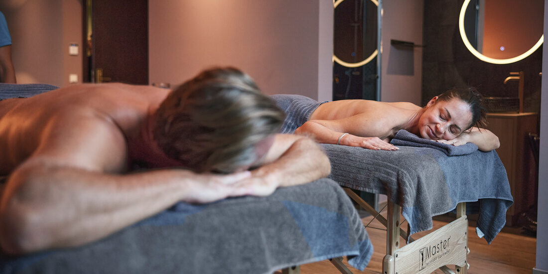 Ein paar liegt gemeinsam entspannt auf einem Massagetisch im Wellnessbereich des Hotel Holzapfels in Niederbayern.