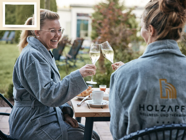 Zwei Frauen genießen Wein auf der Poolterrasse des 4-Sterne-Hotels Holzapfel in Bad Füssing.