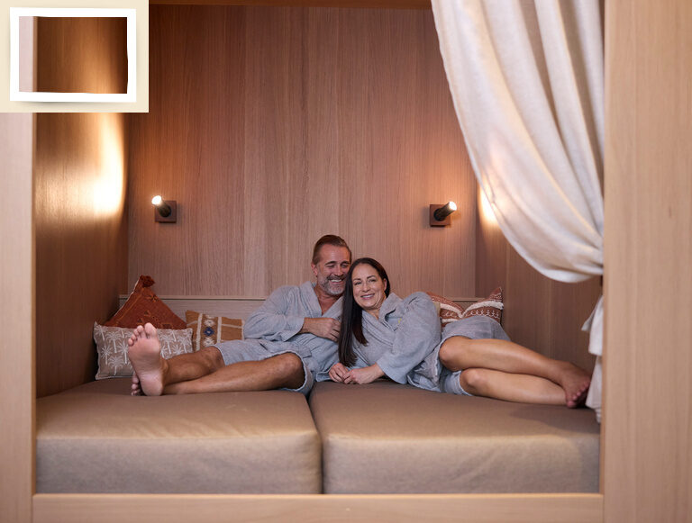 Der Ruhebereich im Thermenhotel Holzapfel in Bayern zeigt ein Paar, das auf einem luxuriösen Bett im geschmackvoll dekorierten Zimmer liegt.