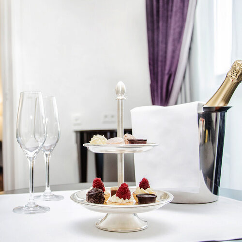 Weingläser und ein kleines Buffet mit Desserts als zentrale Elemente auf einem festlichen Tisch in der Suite Gala des Gesundheitshotels Holzapfel in Niederbayern.