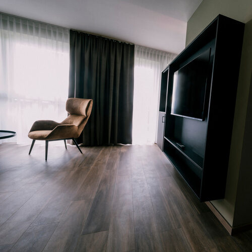 Geräumiges Schlafzimmer in der Suite Golden Delicious des Wellnesshotels Holzapfel in Bad Füssing mit modernem Interieur und Fernseher.