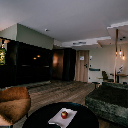 gemütliche Wohnecke mit stilvoller Beleuchtung und Couch zum Entspannen in der Suite golden delicious des Thermenhotels Holzapfel in Bayern.