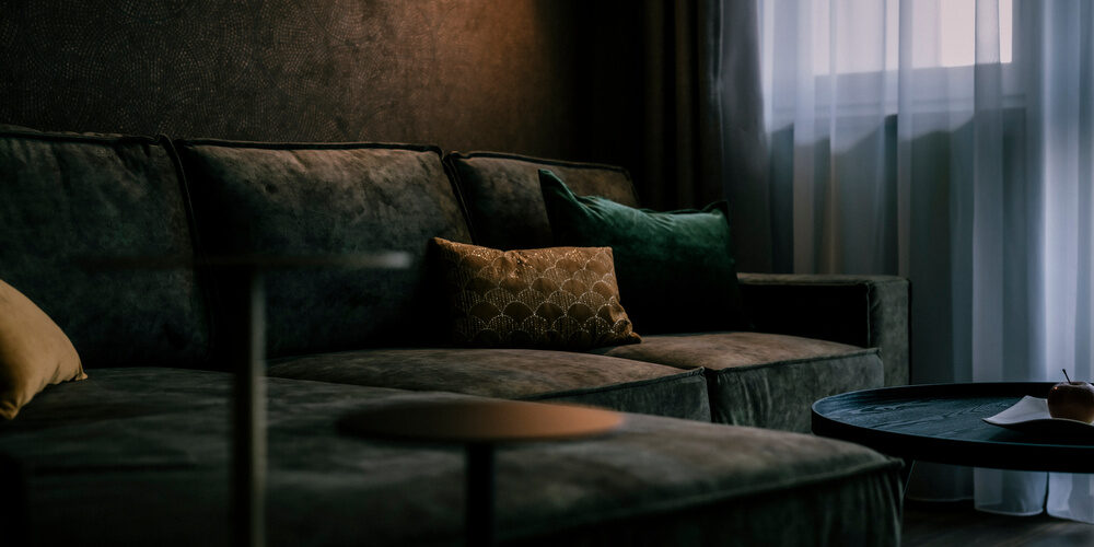 Gemütliches Wohnzimmer in der Suite Golden Delicious des Thermenhotels Holzapfel im Rottal mit bequemer Couch und Couchtisch.