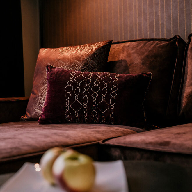 Äpfel liegen auf einem weißen Teller vor der gemütlichen Couch der Suite Goldrenette des Hotel Holzapfel in Niederbayern.