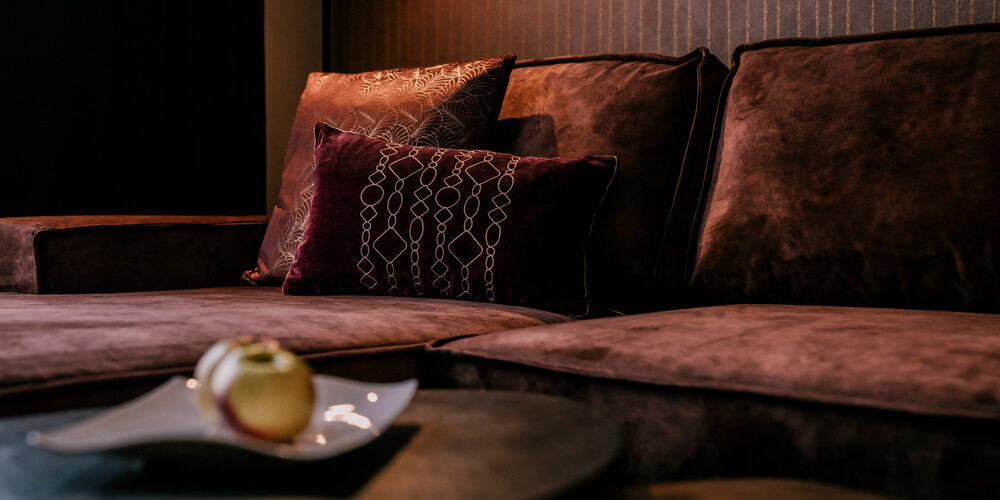 Wohnlicher Raum der Suite Pink Lady mit gemütlichem braunen Sofa im Hotel Holzapfel in Niederbayern..