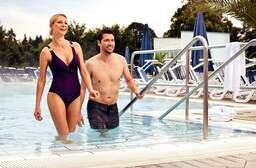 Ein Paar geht lächelnd nach der Entspannung im Schwimmbecken der Therme Eins in Bad Füssing heraus.