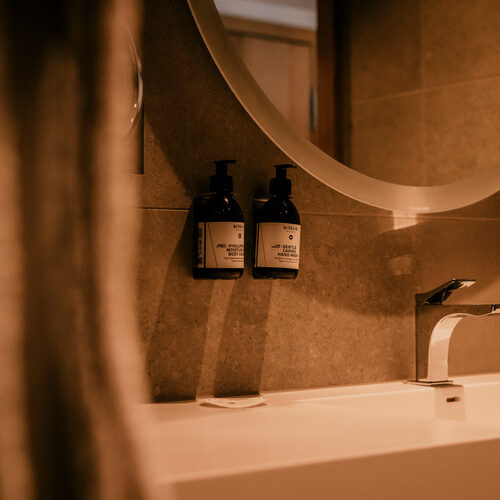 Ein modernes Waschbecken mit eleganter Armatur und Seifenspendern im hellen Badezimmer Einzelzimmer Comfort des Thermenhotels Holzapfel im Rottal.